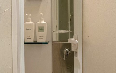 シャワー室の扉の脇のガラス棚に、Badens のシャンプーとリンスのボトルが2本並んでいる