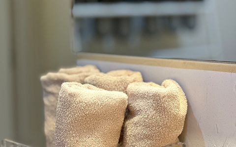 棚に丸めて重ねられた、生成り色のタオル