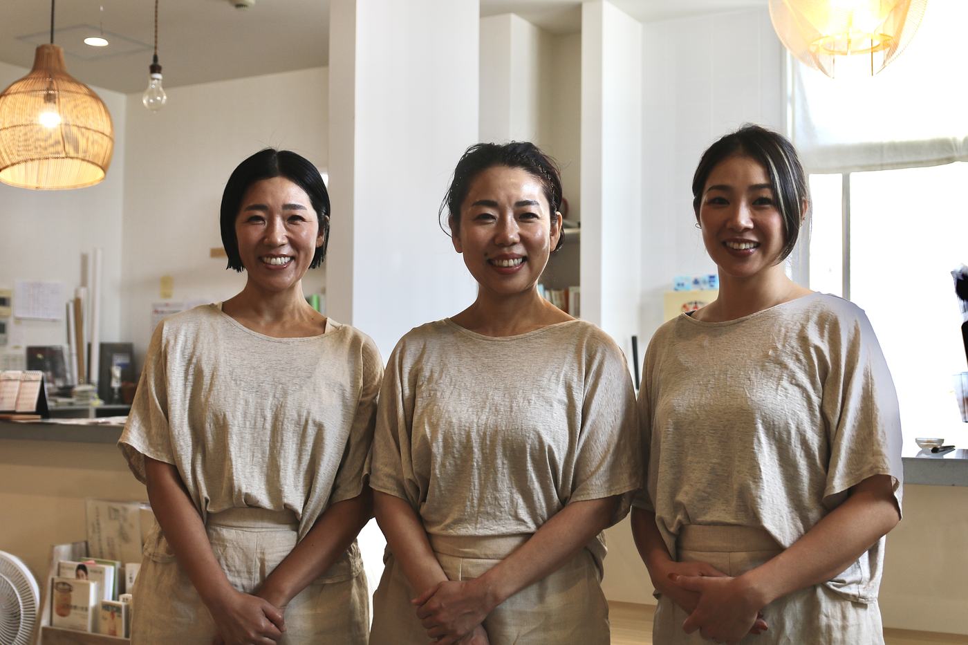 明るい受付の前で、並んで笑うスタッフ3人