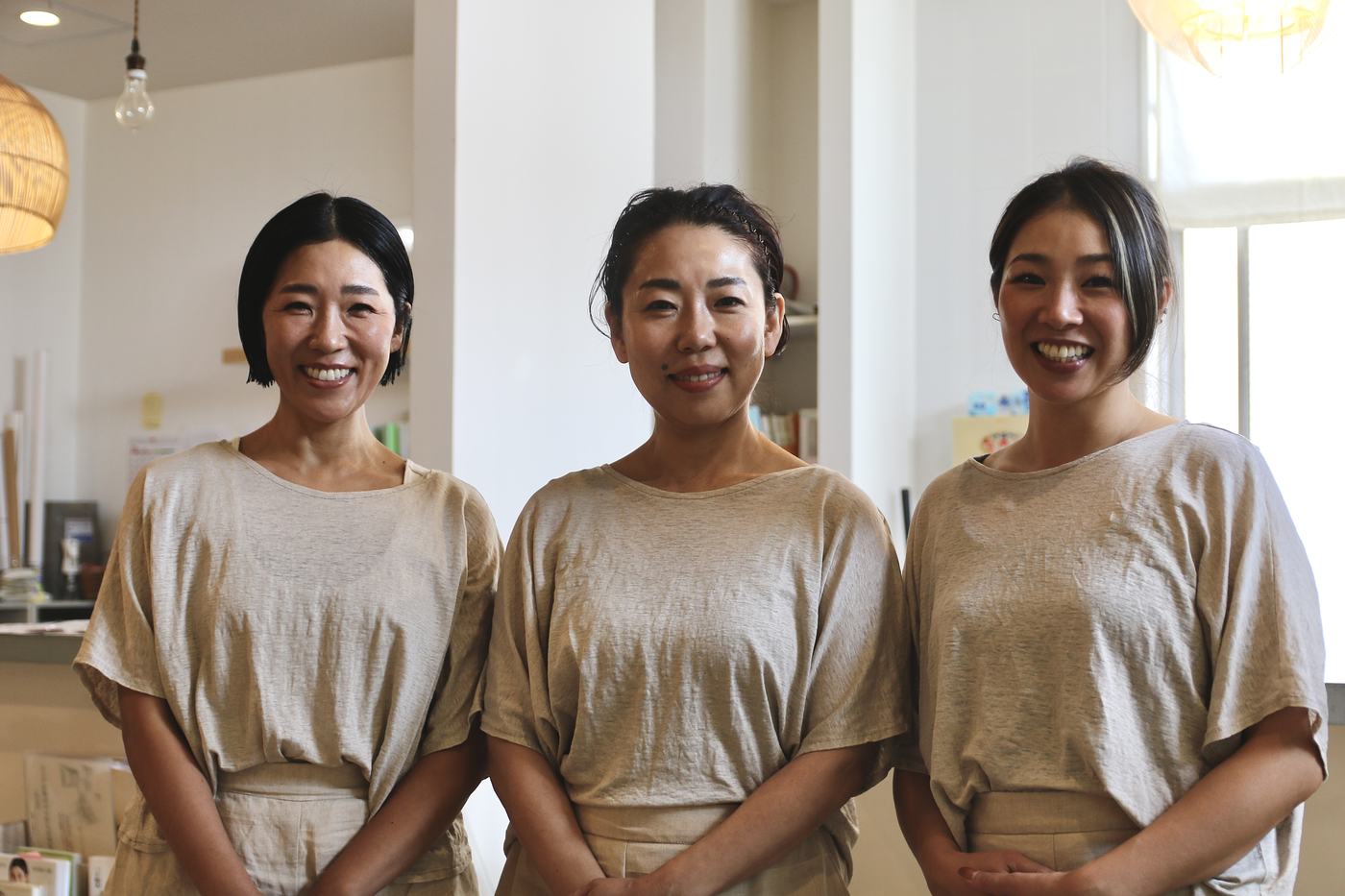 おそろいの生成りの服を着た、osjo のスタッフ3人