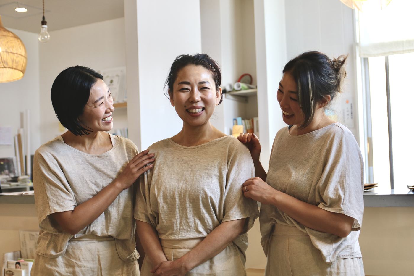 生成りの服をそろえたスタッフ3人が、笑い合っている