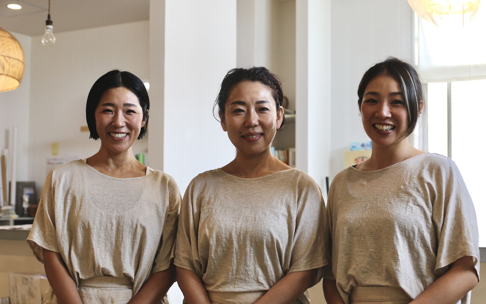 おそろいの生成りの服を着た、osjo のスタッフ3人
