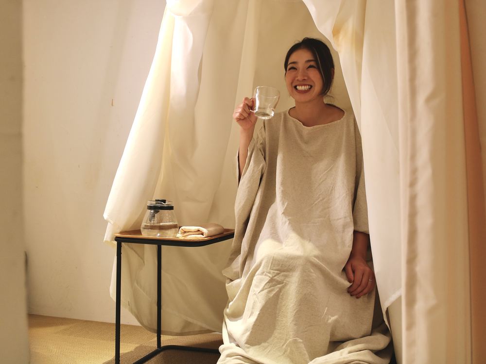 よもぎ蒸しの最中に、グラスを手に笑顔を見せる