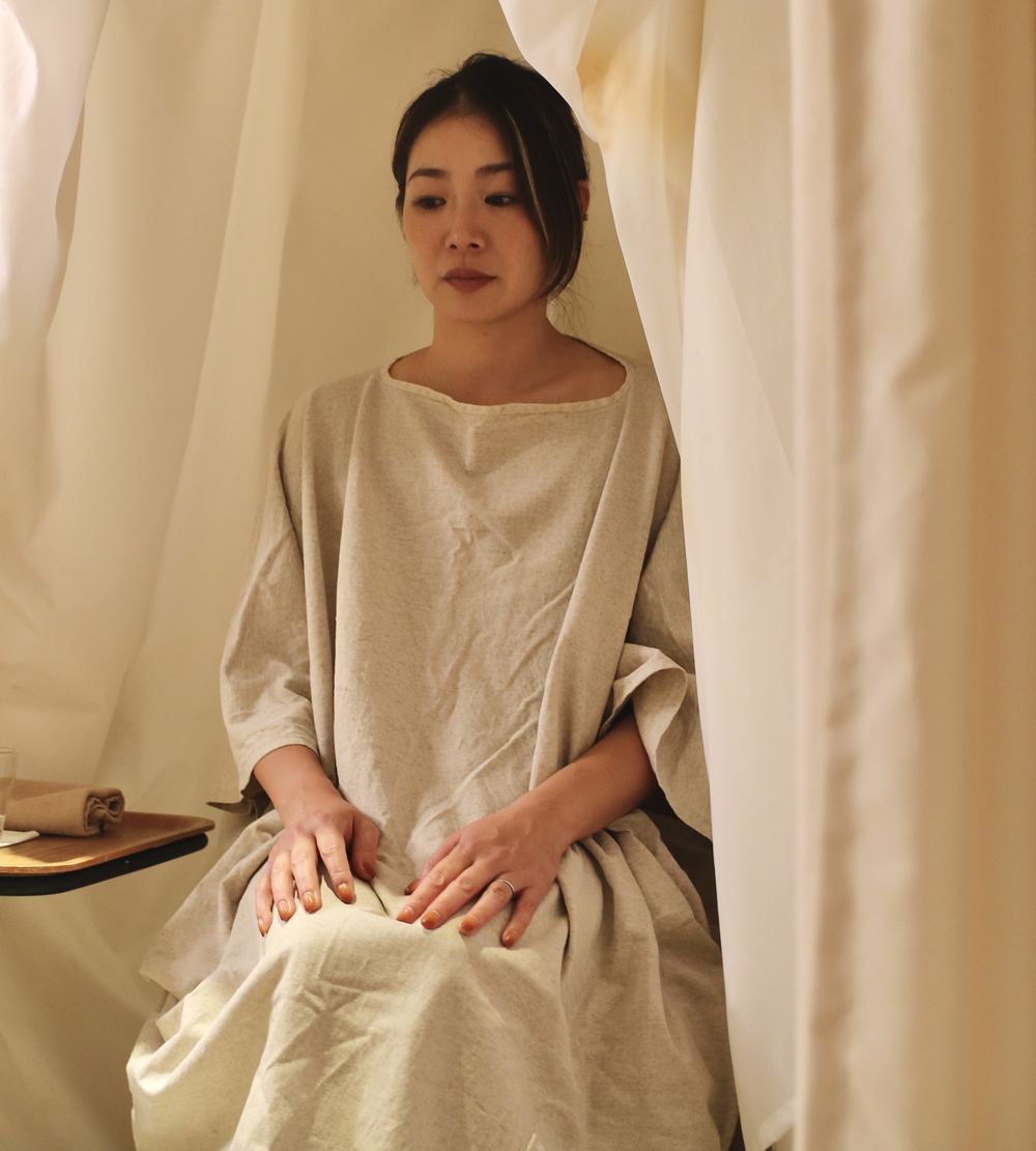 ガウンを着て、よもぎ蒸しの椅子に腰かけている